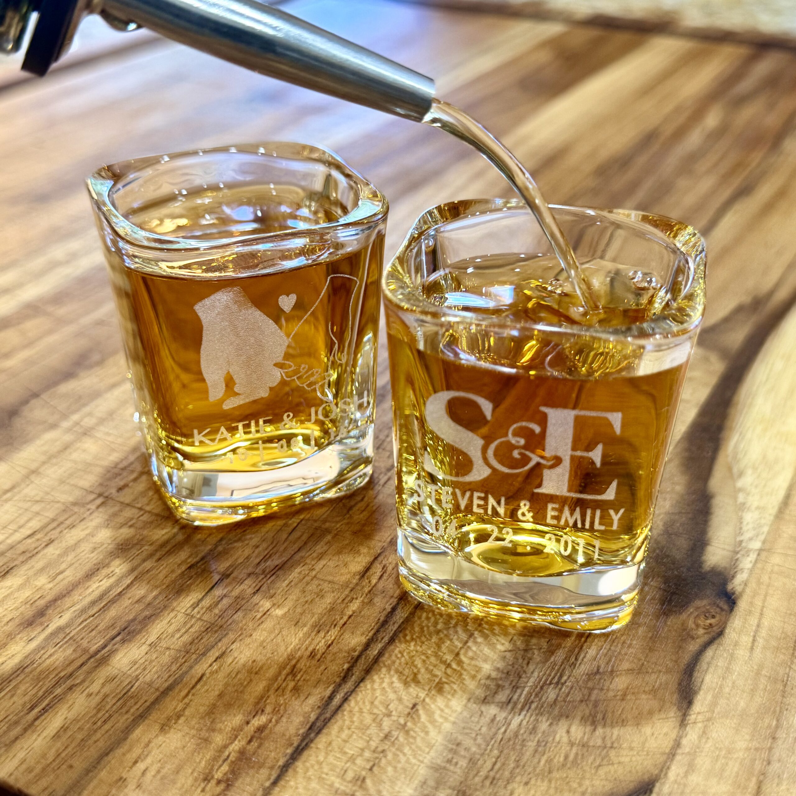 Two custom engraved shot glasses with drink being poured
